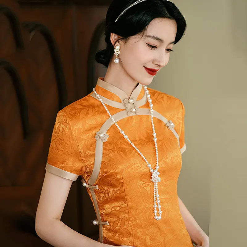 Woman wearing an orange traditional chinese outfit with pearl accessories against a blurred background