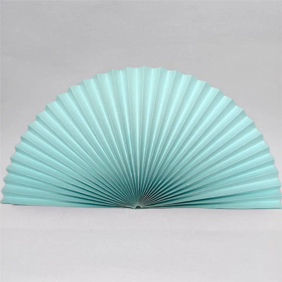 A light aqua pleated folding hand fan, shown partially opened against a neutral light gray background.