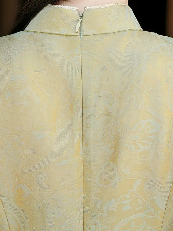 Close-up of the back of a pale yellow A-Line Jacquard Short Sleeve Qipao with Embroidered Cuff with a high collar and a central zipper, showing a subtle paisley pattern.