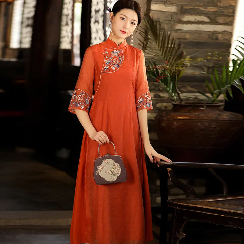 a chinese Woman in an orange  Modern A Line Loose Cheongsam Qipao Dress with Sheer Sleeve holding a handbag in a rustic setting