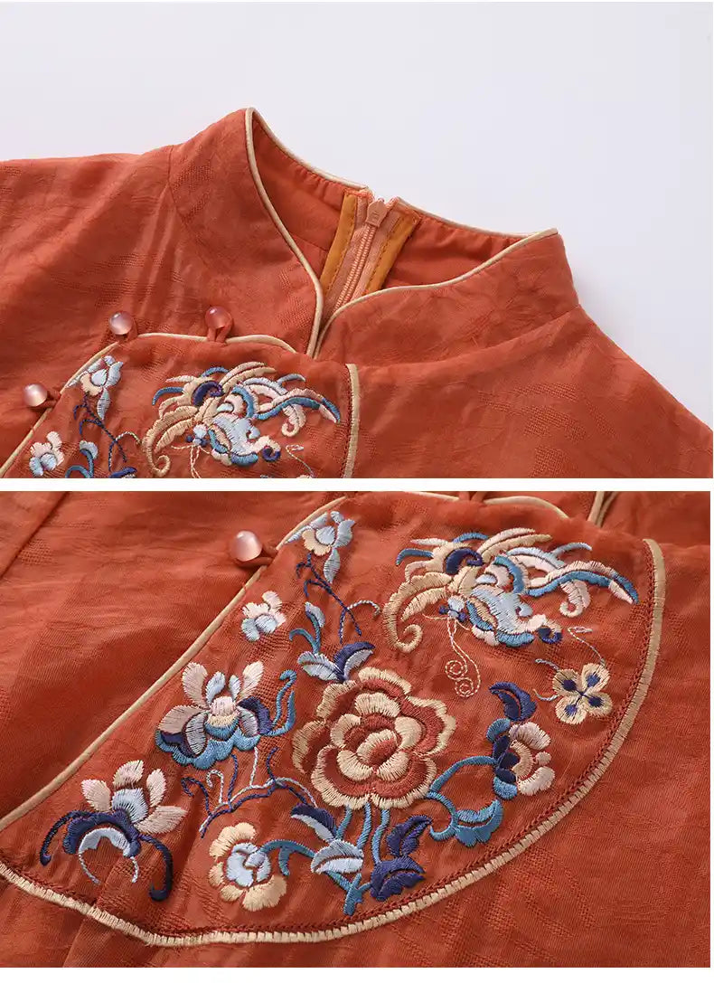 Close-up of an orange garment with intricate floral embroidery on a white background