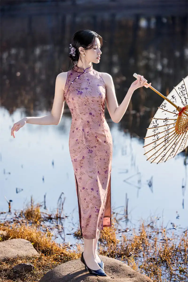 Woman in a floral pink Modern Chinese Mandarin Dress Sleeveless Qipao holding an umbrella by a body of water