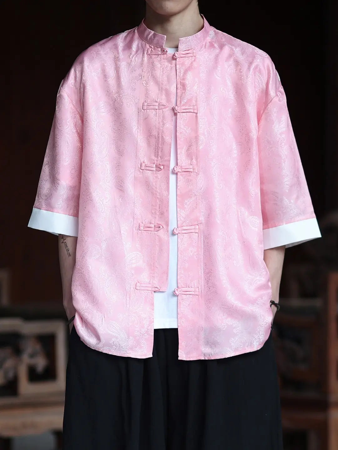 Person wearing a pink traditional-style Modern New Chinese Style Men's Half Sleeve Jacquard Tang Shirt  with white trim on a blurred background