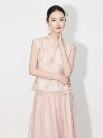 Woman wearing a light pink traditional New Chinese Style - Sleeveless Asymmetric Top & Maxi Skirt Set outfit with floral patterns on a white background