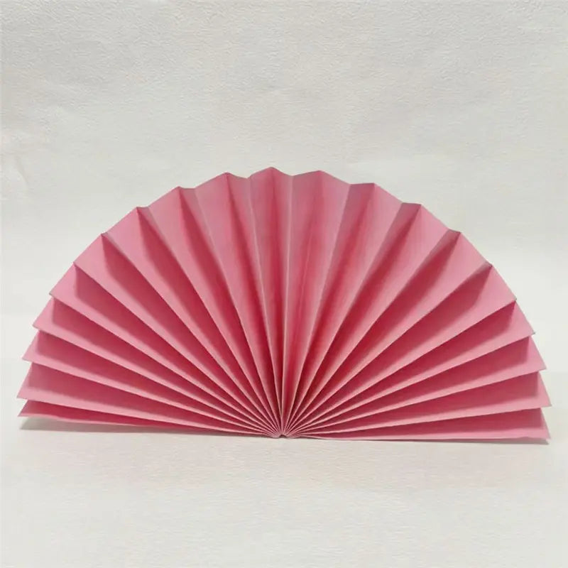 A pink pleated paper fan or decorative folding fan, shown fully opened against a plain light background.