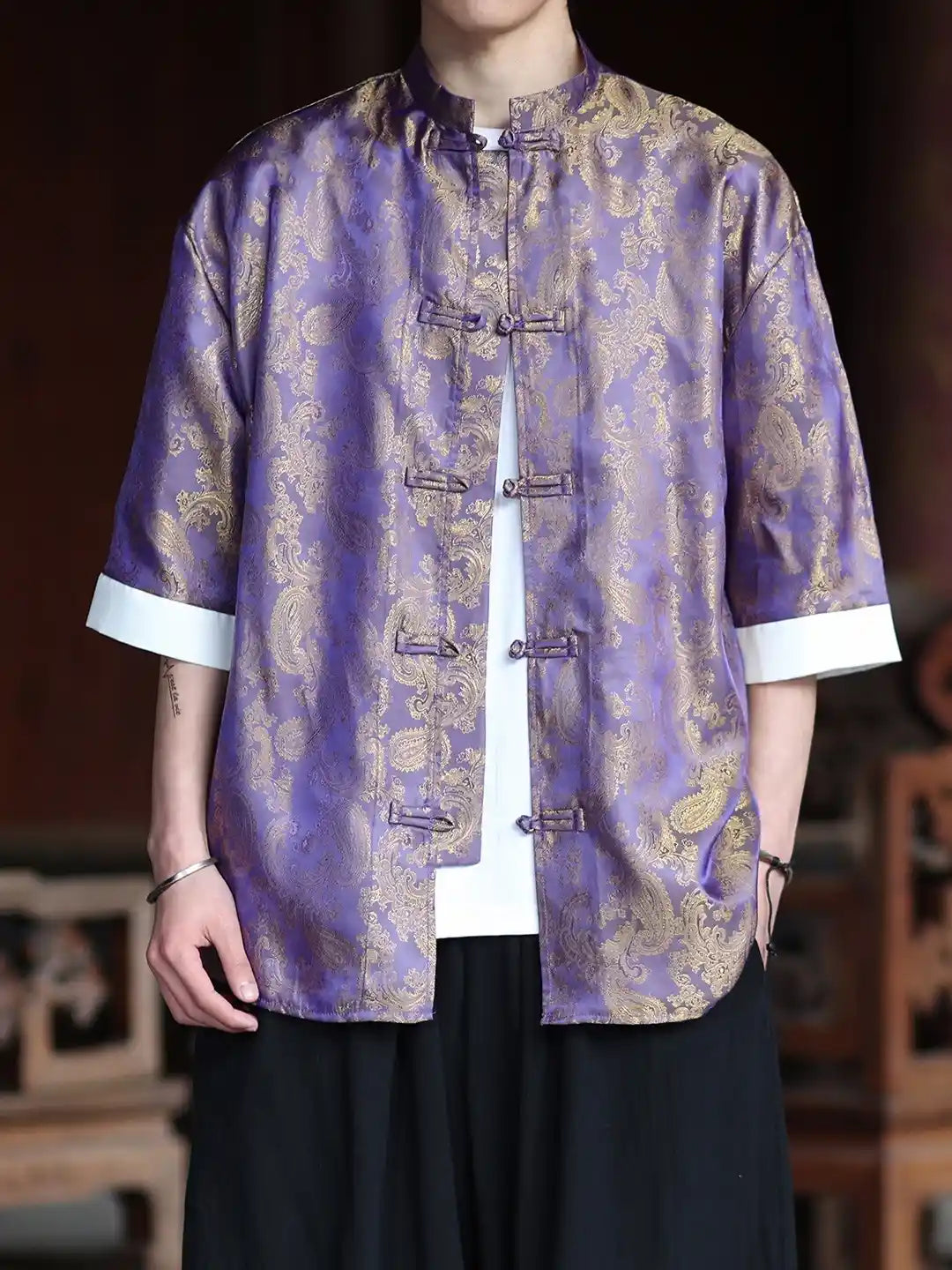 Person wearing a traditional purple and gold patterned  Modern New Chinese Style Men's Half Sleeve Jacquard Tang Shirt with white cuffs.