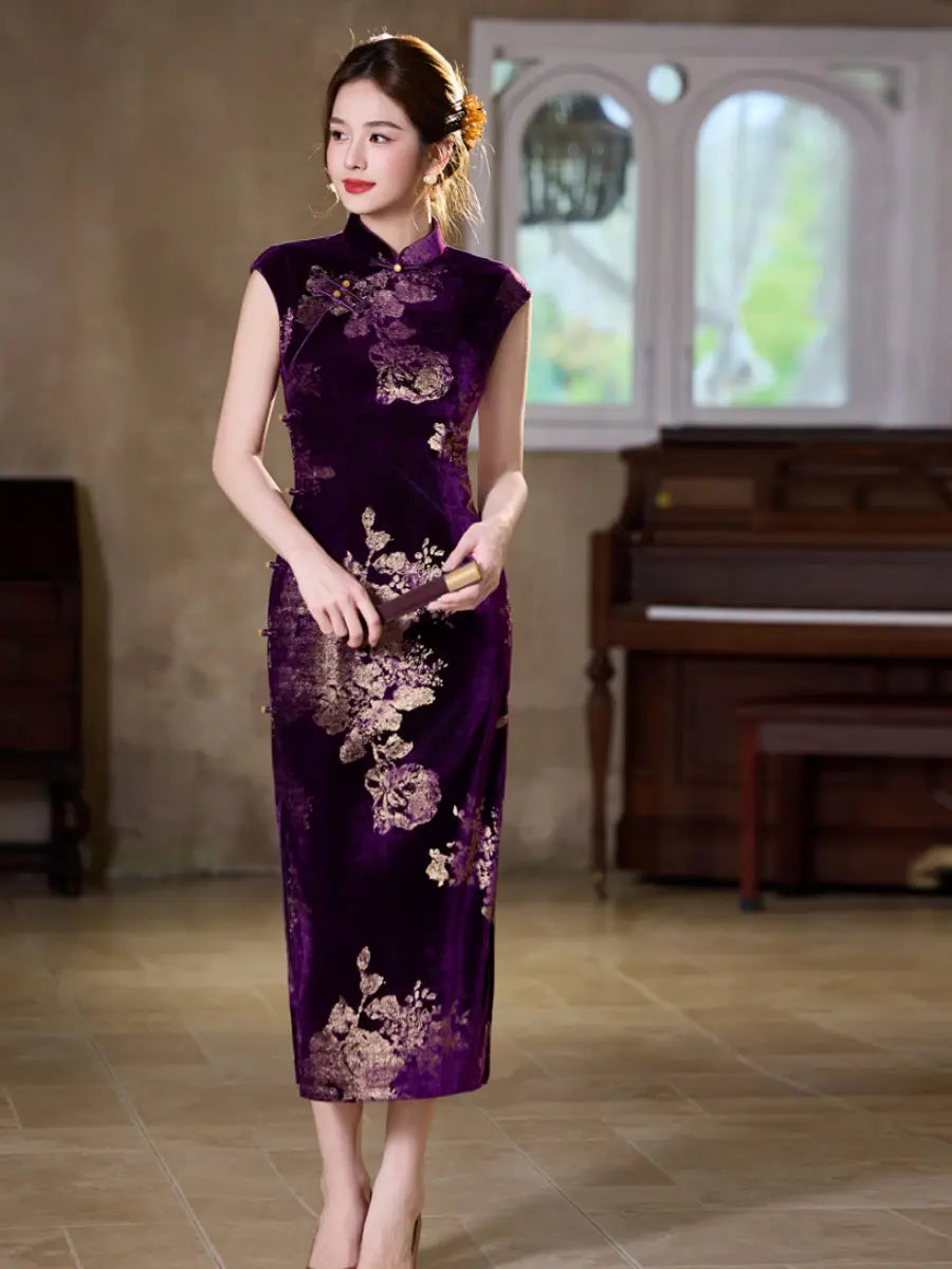 A woman stands indoors wearing a sleeveless, floor-length purple cheongsam with gold floral embroidery. The dress has a rich velvet-like texture and features gold-colored floral patterns running down the front.