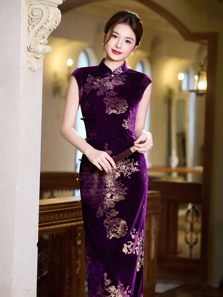 A woman wearing a sleeveless purple velvet cheongsam with gold floral embroidery, standing in a warm, classical indoor setting with wooden furniture and arches.