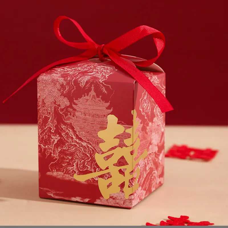 Red Gold Foil Double Happiness Chinoiserie Wedding Favor Boxes   with gold characters and a red ribbon on a beige surface with a red background