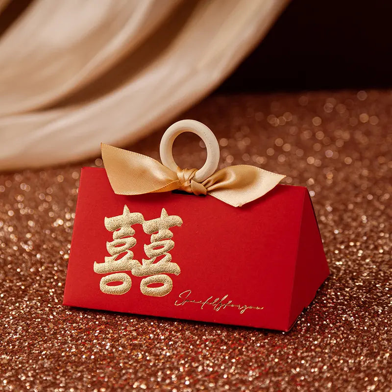 Red Luxury Gold Foil Double Happiness Favor Boxes gift box with gold bow and Chinese characters on a glittery surface