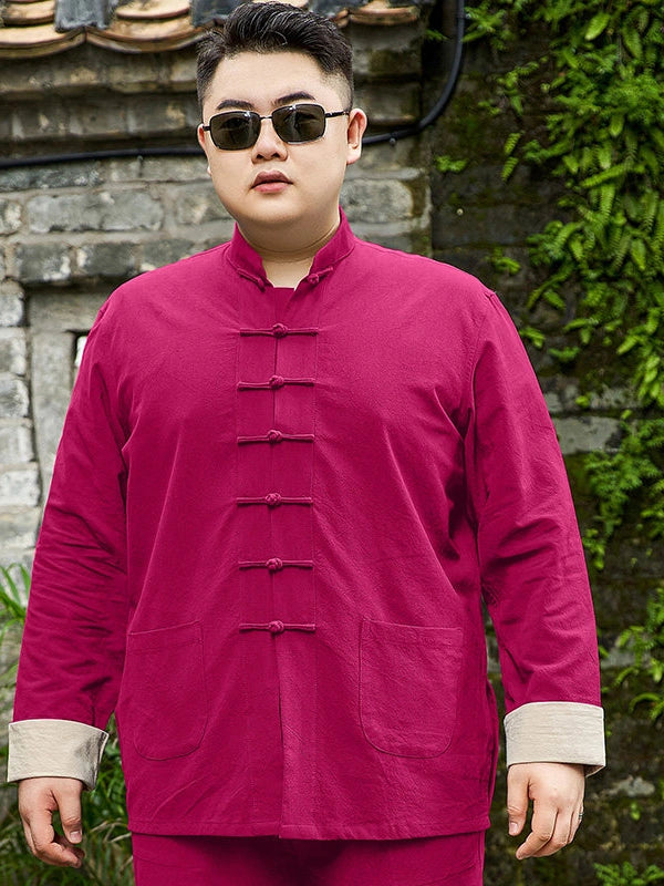 A man wearing a magenta-pink plus size traditional Chinese-style jacket with beige turned-back cuffs and sunglasses, standing outdoors in front of a stone wall and green foliage.