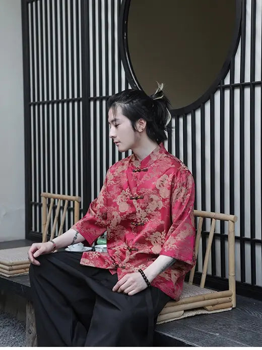 Person wearing a red traditional Modern Chinese Dragon Print Ice Silk Half Sleeve Tang Shirt outfit sitting on a bench with a black and white striped wall in the background.