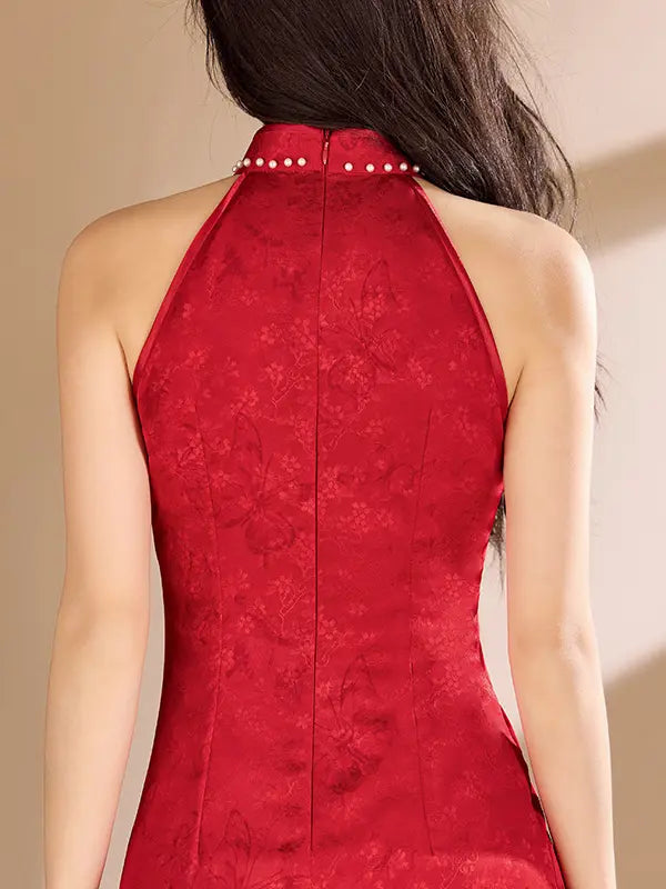 A close-up back view of a woman wearing a red Pearl-Trimmed Sleeveless Halter Jacquard Satin Qipao  with a high collar decorated with small white pearls and a subtle tonal floral jacquard pattern.
