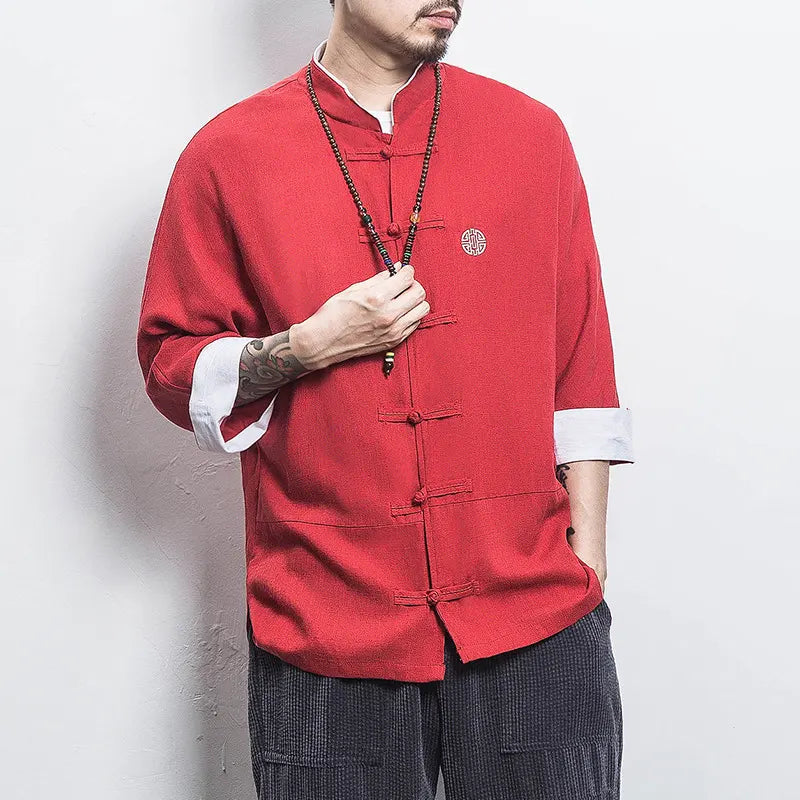 Person wearing a red traditional Three-Quarter Sleeve Zen Heritage Linen-Blend Kong Fu Tang Shirt jacket with white cuffs against a plain background