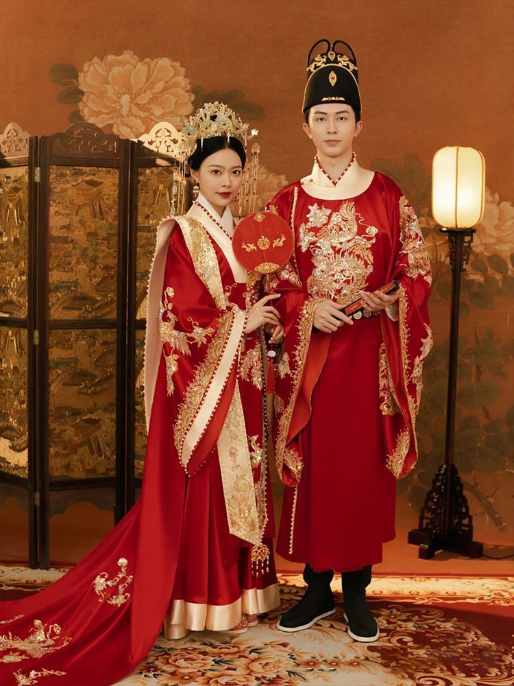 bride and groom in traditional Chinese wedding attire Imperial Chinese Ming Dynasty Wedding Hanfu Set  standing in a decorated room.