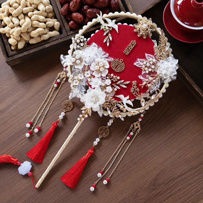 Traditional Chinese Bridal Round Hand Fan with Tassels with red and gold elements on a wooden surface.