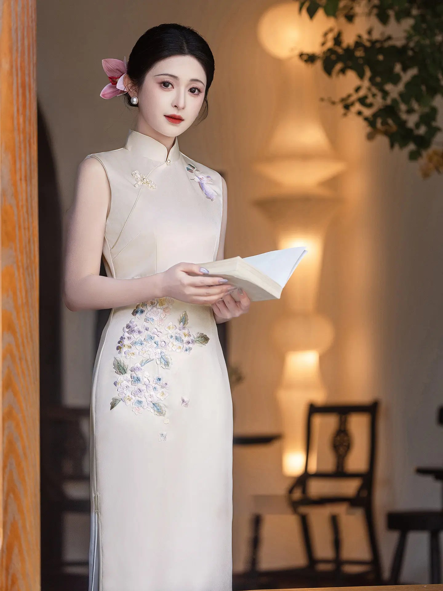 Woman in a traditional white  Luxury Embroidered New Chinese Style Sleeveless cheongsam Qipao Dress with floral patterns in an indoor setting