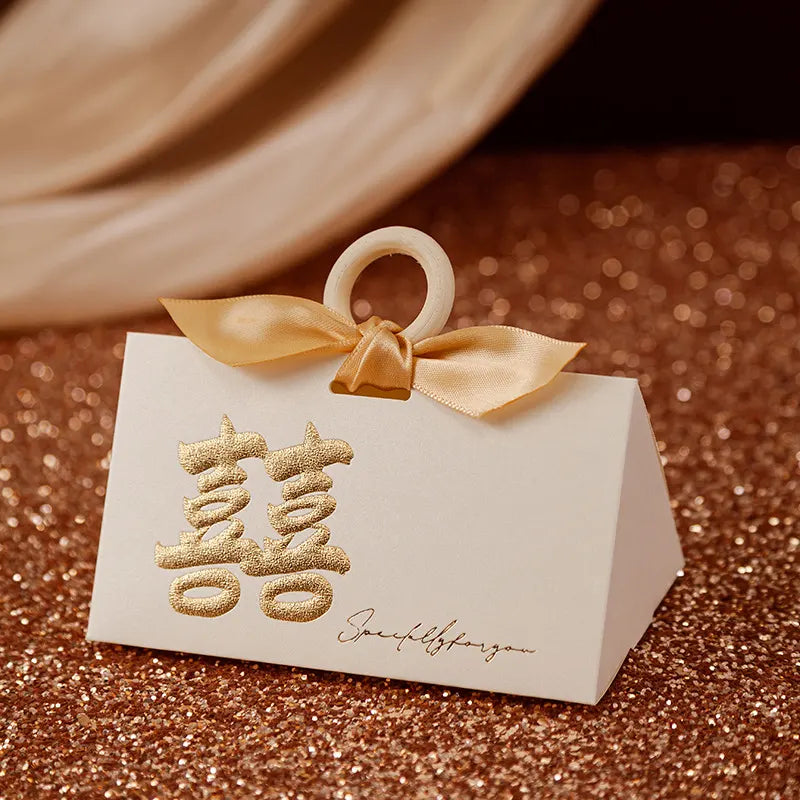 White Luxury Gold Foil Double Happiness Favor Boxes gift box with gold ribbon and Chinese characters on a glittery brown surface