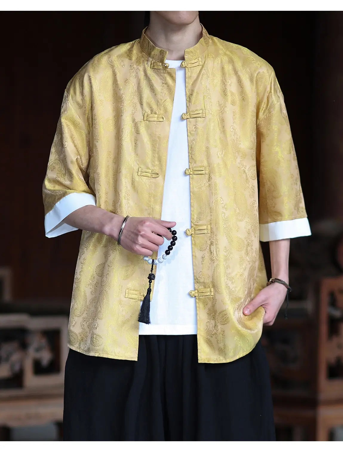 Person wearing a yellow traditional-Modern New Chinese Style Men's Half Sleeve Jacquard Tang Shirt with white cuffs and buttons, standing against a blurred background.