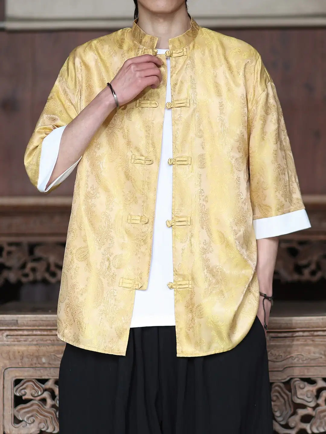 Person wearing a yellow traditional Modern New Chinese Style Men's Half Sleeve Jacquard Tang Shirt jacket with white cuffs and black pants in an indoor setting.