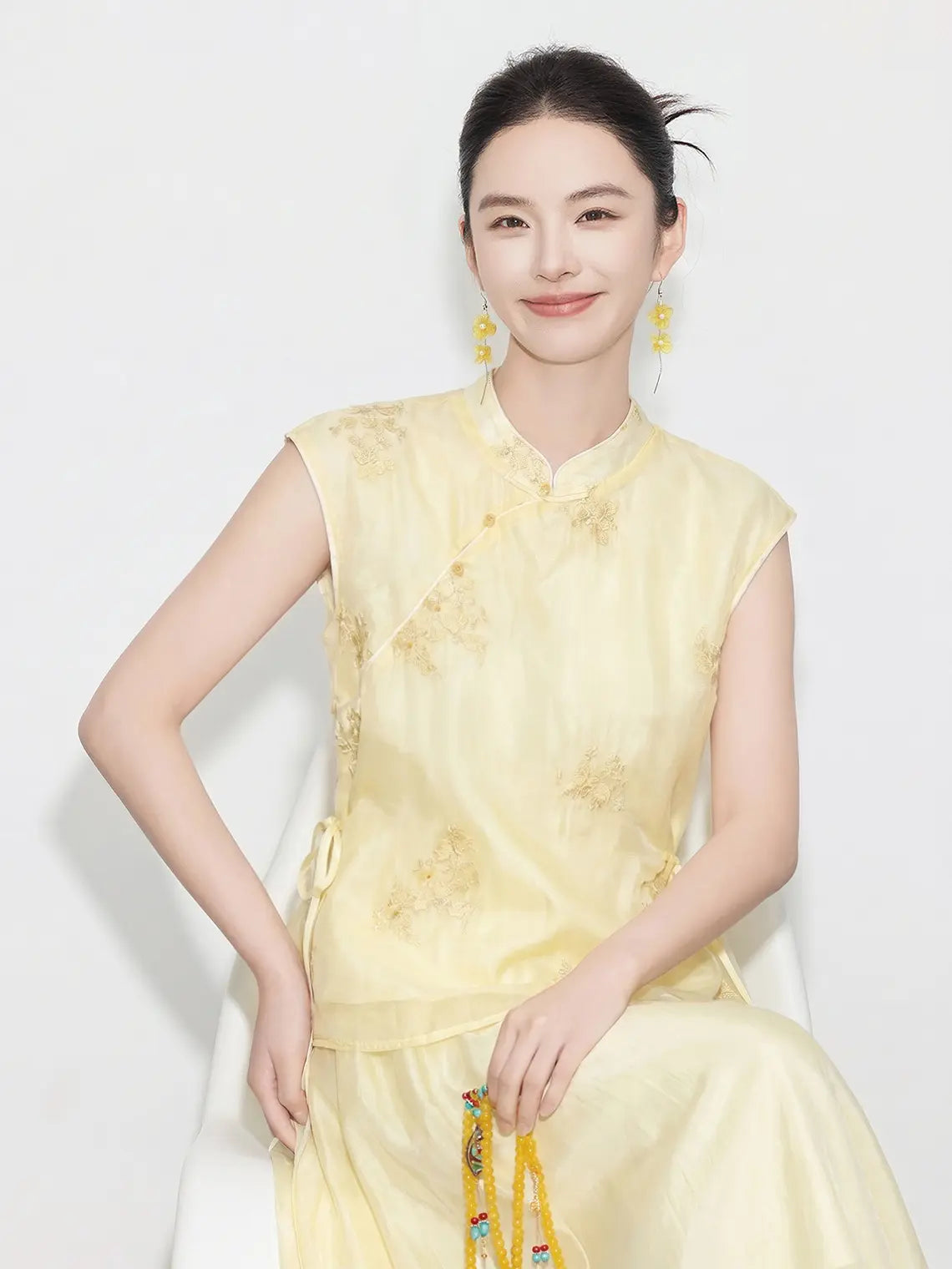 Woman wearing a yellow traditional New Chinese Style - Sleeveless Asymmetric Top & Maxi Skirt Set dress against a white background