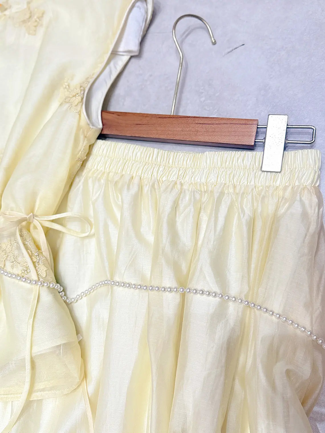 Light yellow New Chinese Style - Sleeveless Asymmetric Top & Maxi Skirt Set  with decorative trim on a hanger against a light background