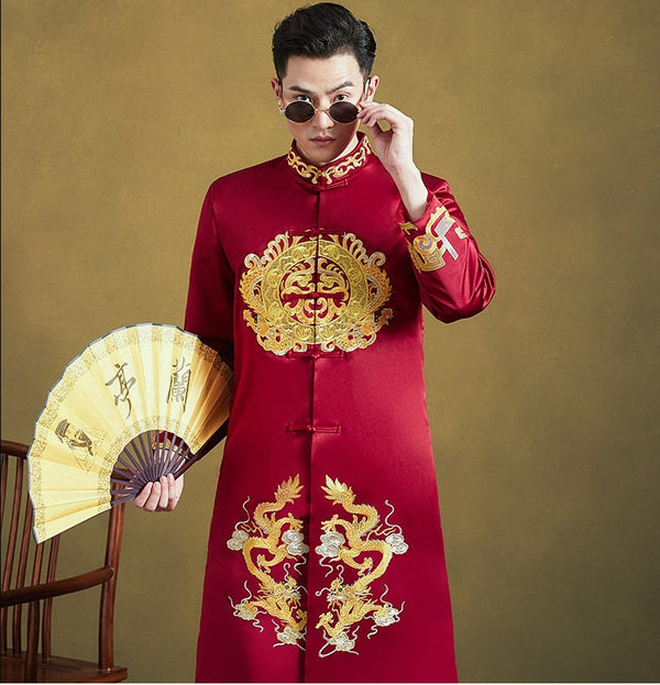 A person wearing a traditional Red & Gold Groom's Dragon Wedding Tang suit  with a mandarin collar and intricate dragon embroideries, holding a yellow fan.