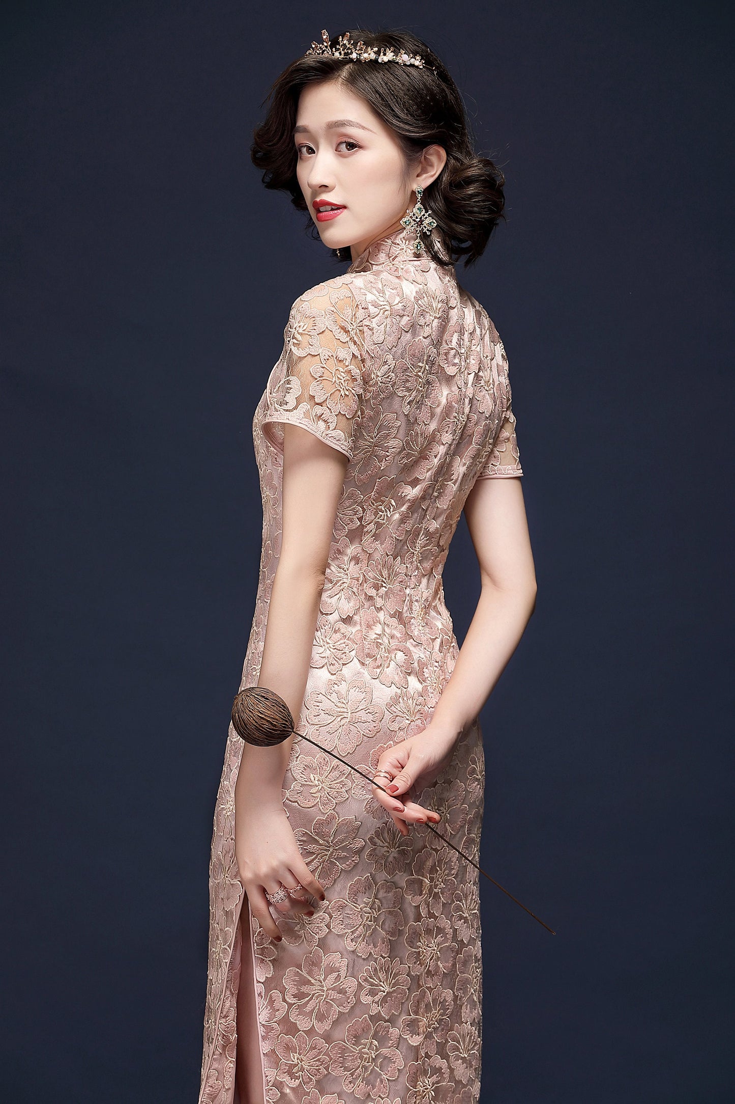 a chinese girl in pink lace cheongsam with flower on hand